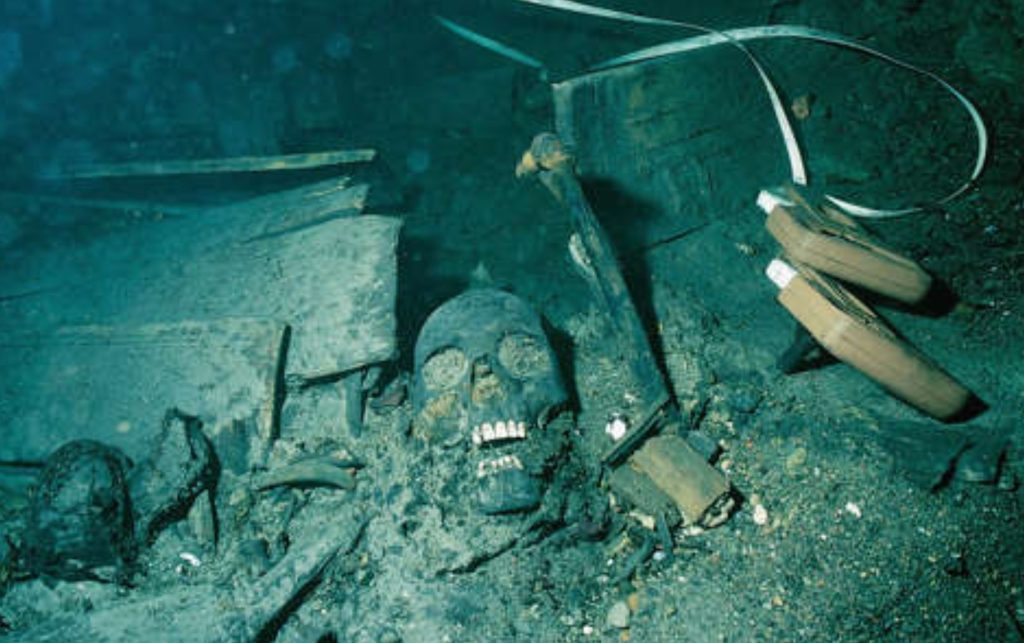Restos de un naufragios en el fondo del mar con artefactos antiguos visibles y arqueólogos marinos investigando objetos históricos únicos encontrados bajo el agua