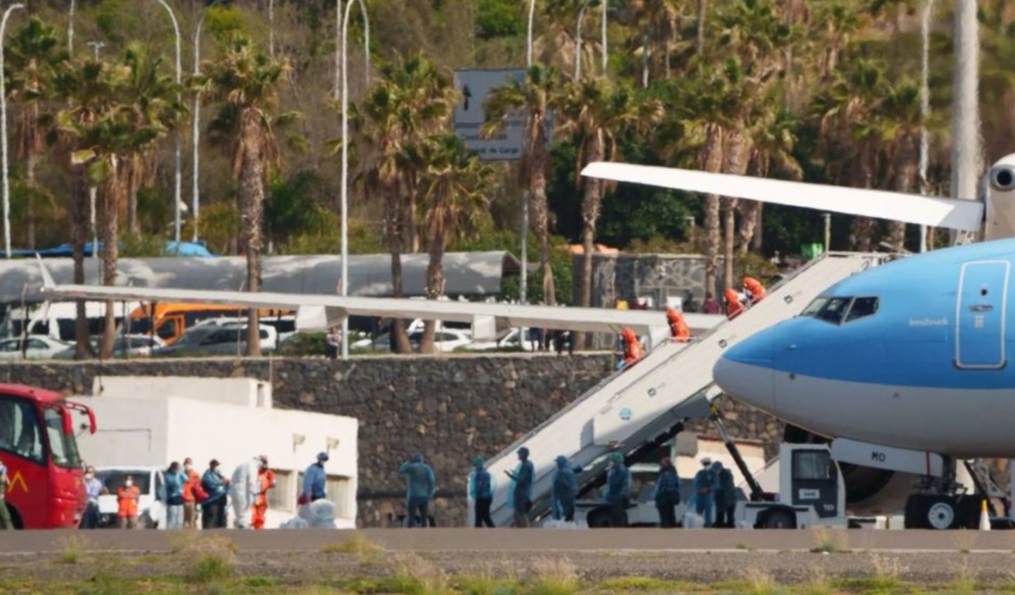 Pasajeros del crucero MV Hondius con chubasqueros azules y mascarillas FFP2 desembarcando del buque fondeado en el puerto de Granadilla, en el sur de Tenerife, hacia los autobuses burbuja de la Unidad Militar de Emergencias en Tenerife - CER