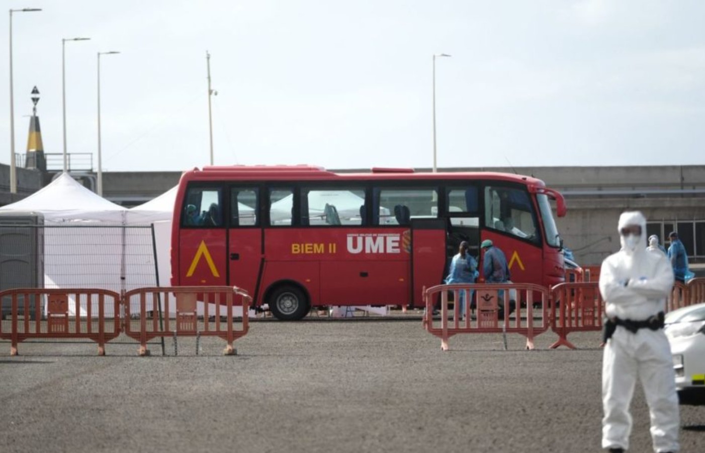 Pasajeros del crucero MV Hondius con chubasqueros azules y mascarillas FFP2 desembarcando del buque fondeado en el puerto de Granadilla, en el sur de Tenerife, hacia los autobuses burbuja de la Unidad Militar de Emergencias en Tenerife