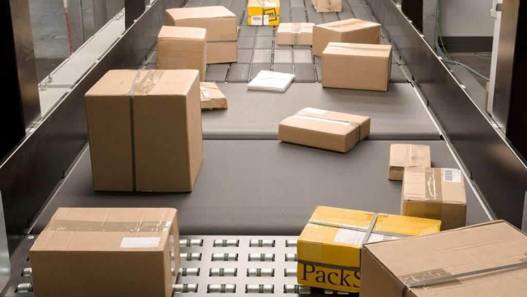 Negocio de paquetería con operario organizando cajas en punto de distribución local